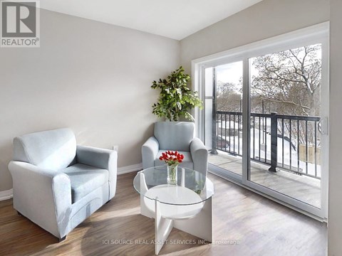 A living room with a grey couch, a white chair, and a glass table with a vase of flowers on it.