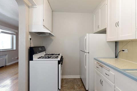 an empty kitchen with white appliances and white cabinets