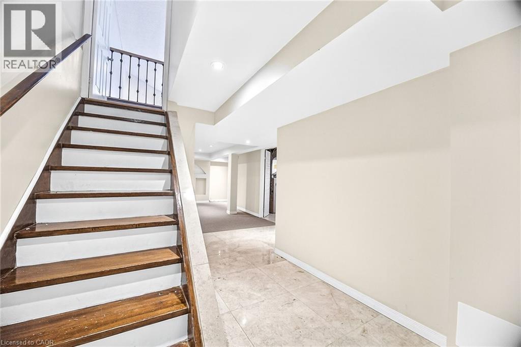A staircase with a wooden handrail and white steps leads to an open space.