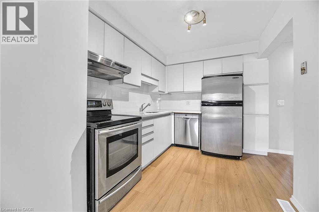 A modern kitchen with stainless steel appliances and wooden flooring.