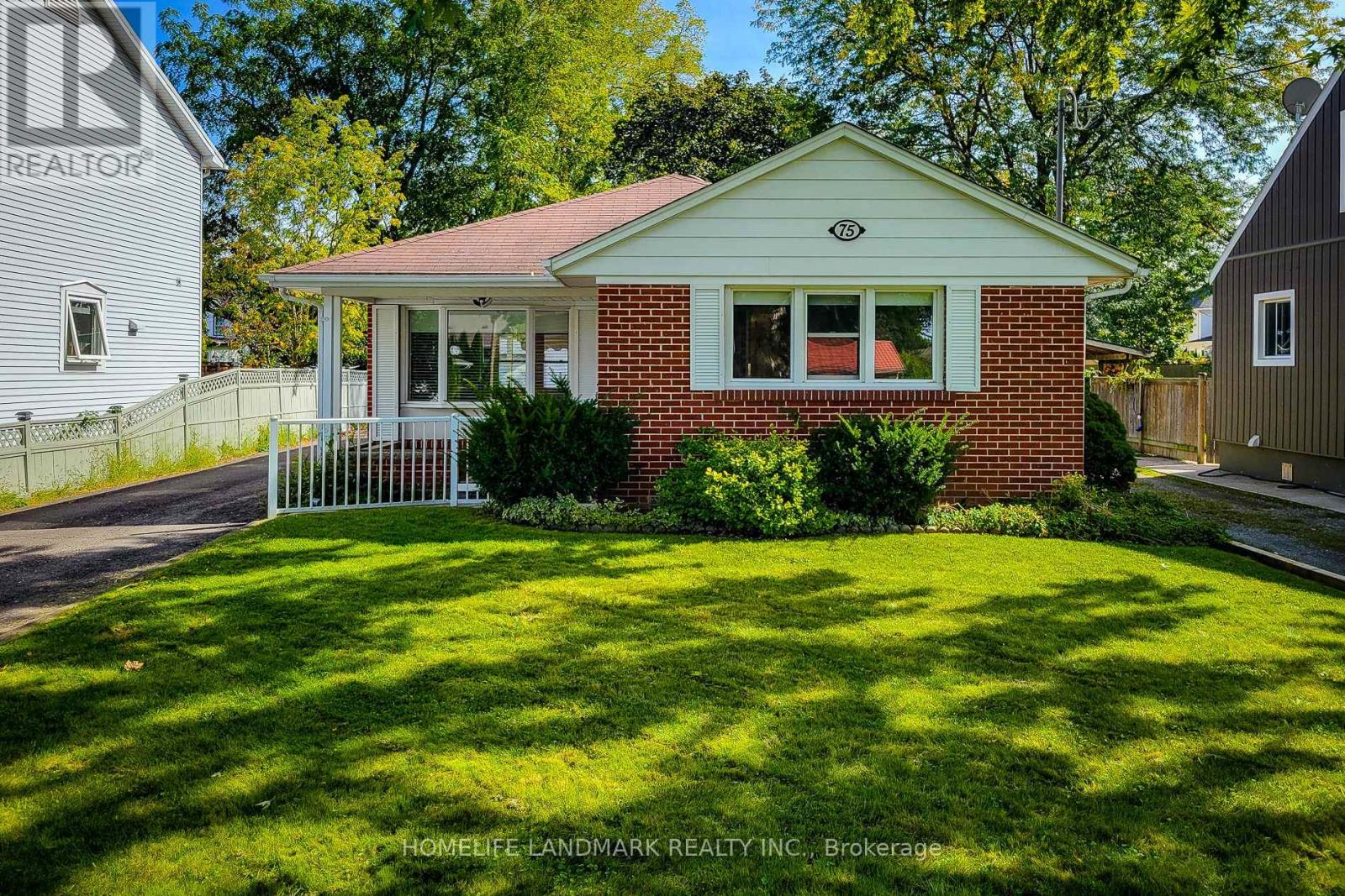 A small house with a red roof and a white fence in front of it.