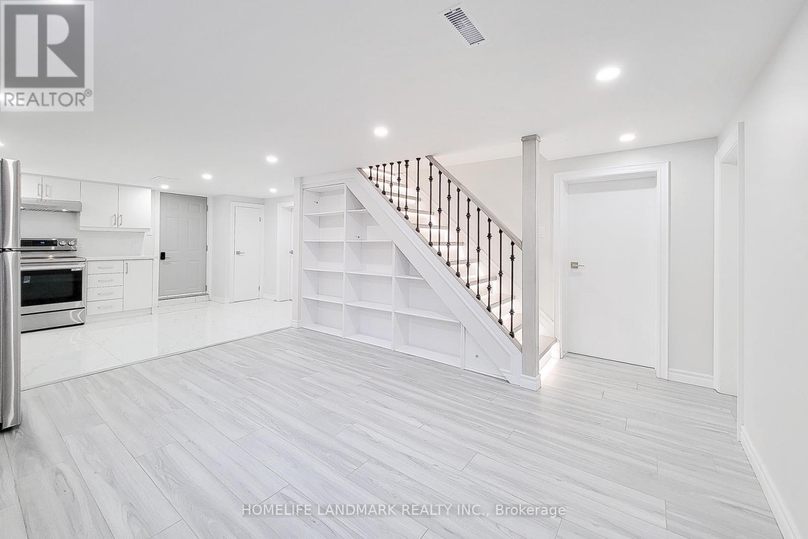 A spacious white room with a staircase and a refrigerator.