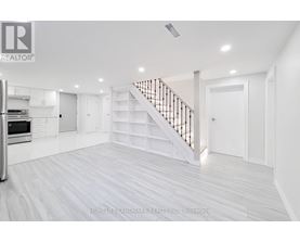 A spacious white room with a staircase and a refrigerator.