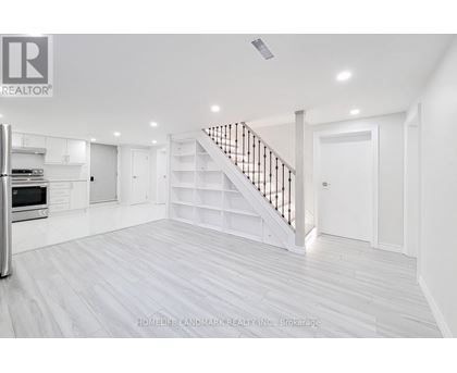 A spacious white room with a staircase and a refrigerator.
