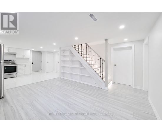 A spacious white room with a staircase and a refrigerator.
