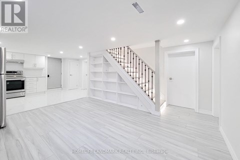 A spacious white room with a staircase and a refrigerator.