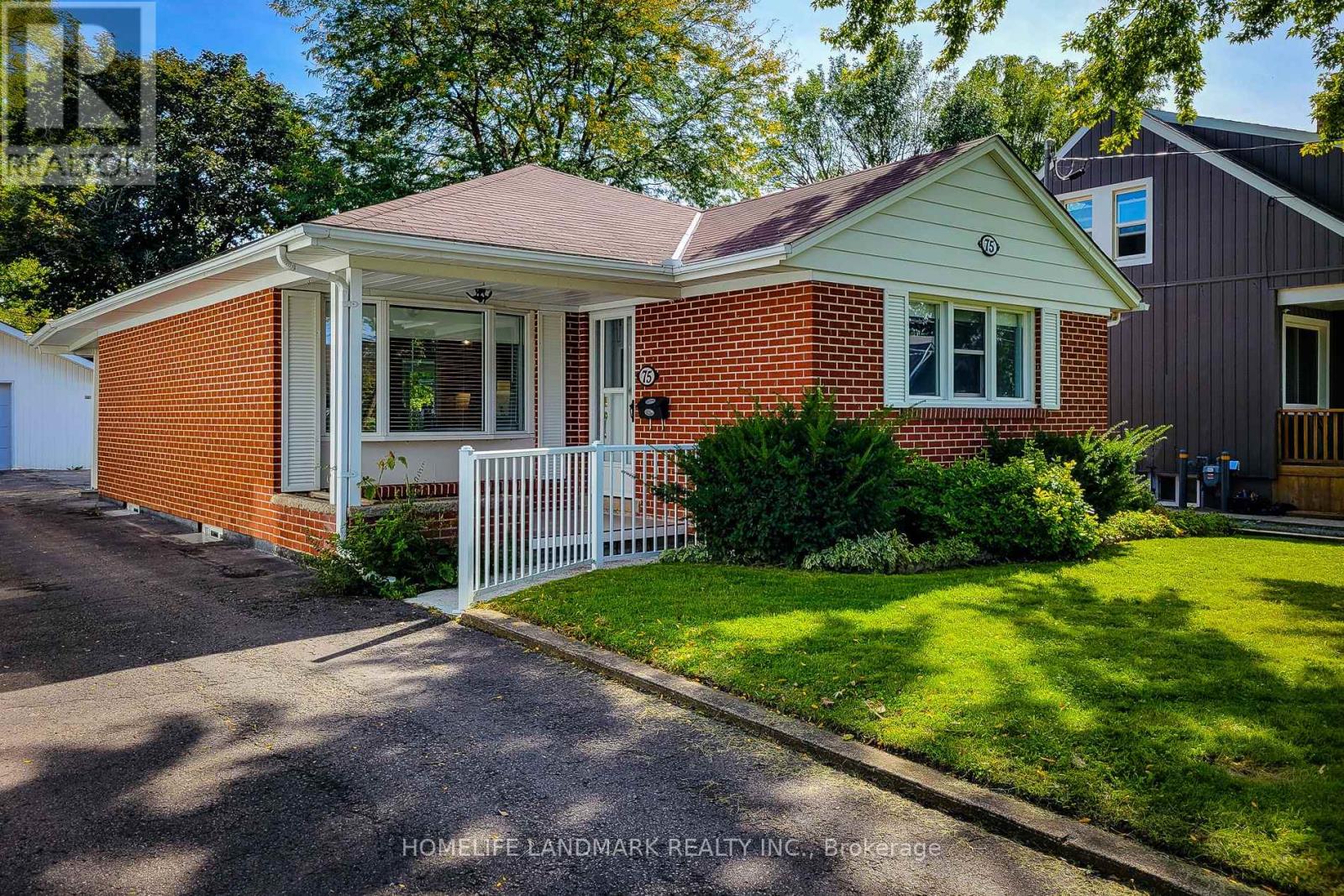 A red brick house with a white fence in front.