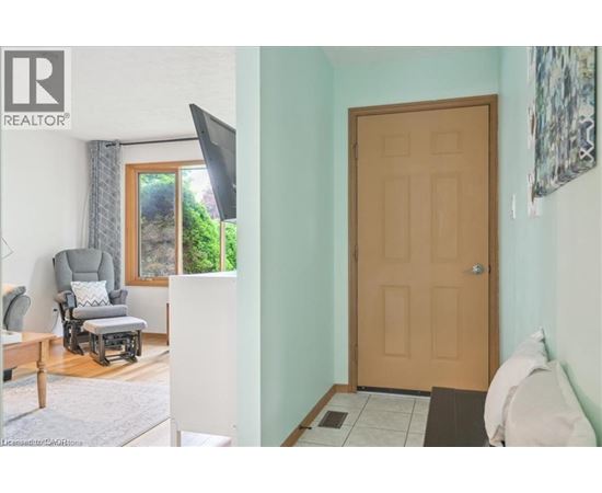 A room with a brown door, a grey chair, and a window with a view of trees.