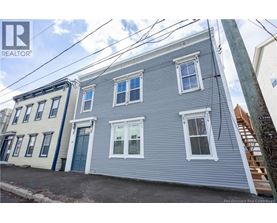 A grey house with a blue door is for sale.