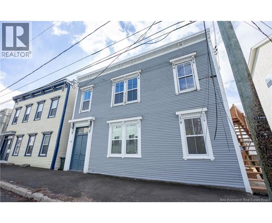 A grey house with a blue door is for sale.