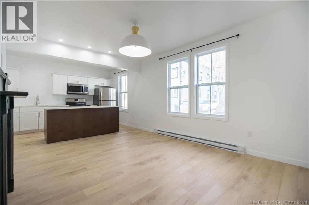 A spacious living room with a kitchen area in the background.