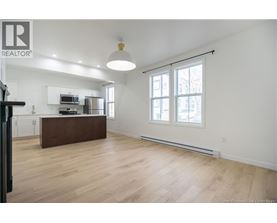 A spacious living room with a kitchen area in the background.