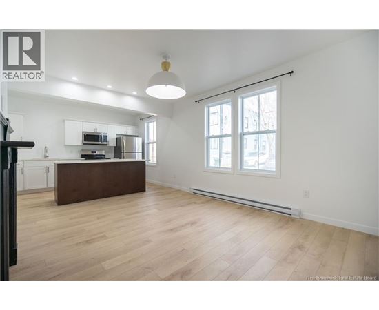 A spacious living room with a kitchen area in the background.