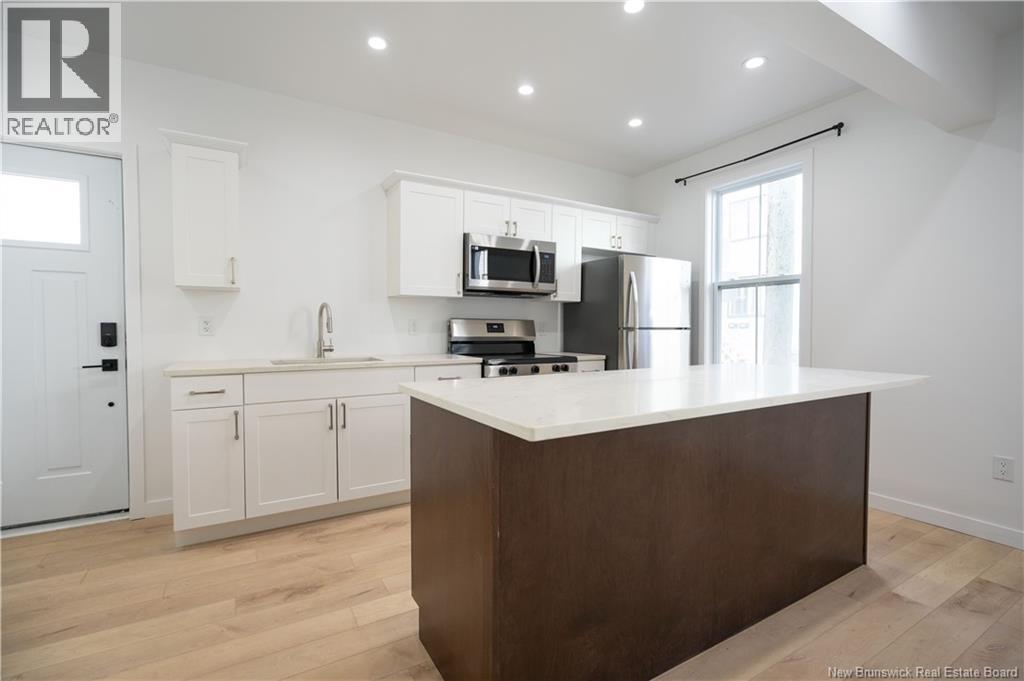 A modern kitchen with white cabinets and a wooden island.
