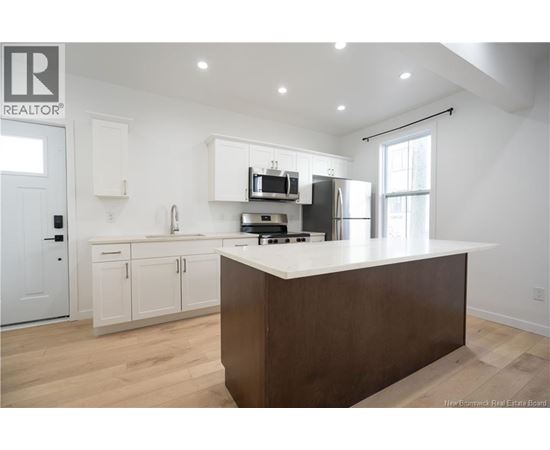 A modern kitchen with white cabinets and a wooden island.