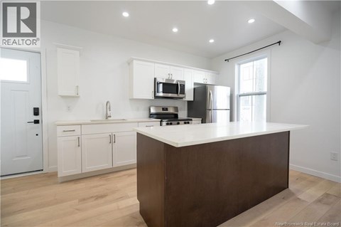A modern kitchen with white cabinets and a wooden island.