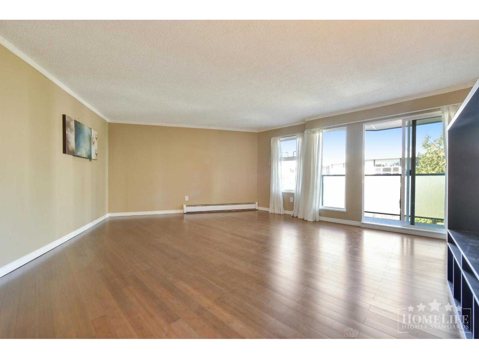 A spacious room with wooden floors and a large window.