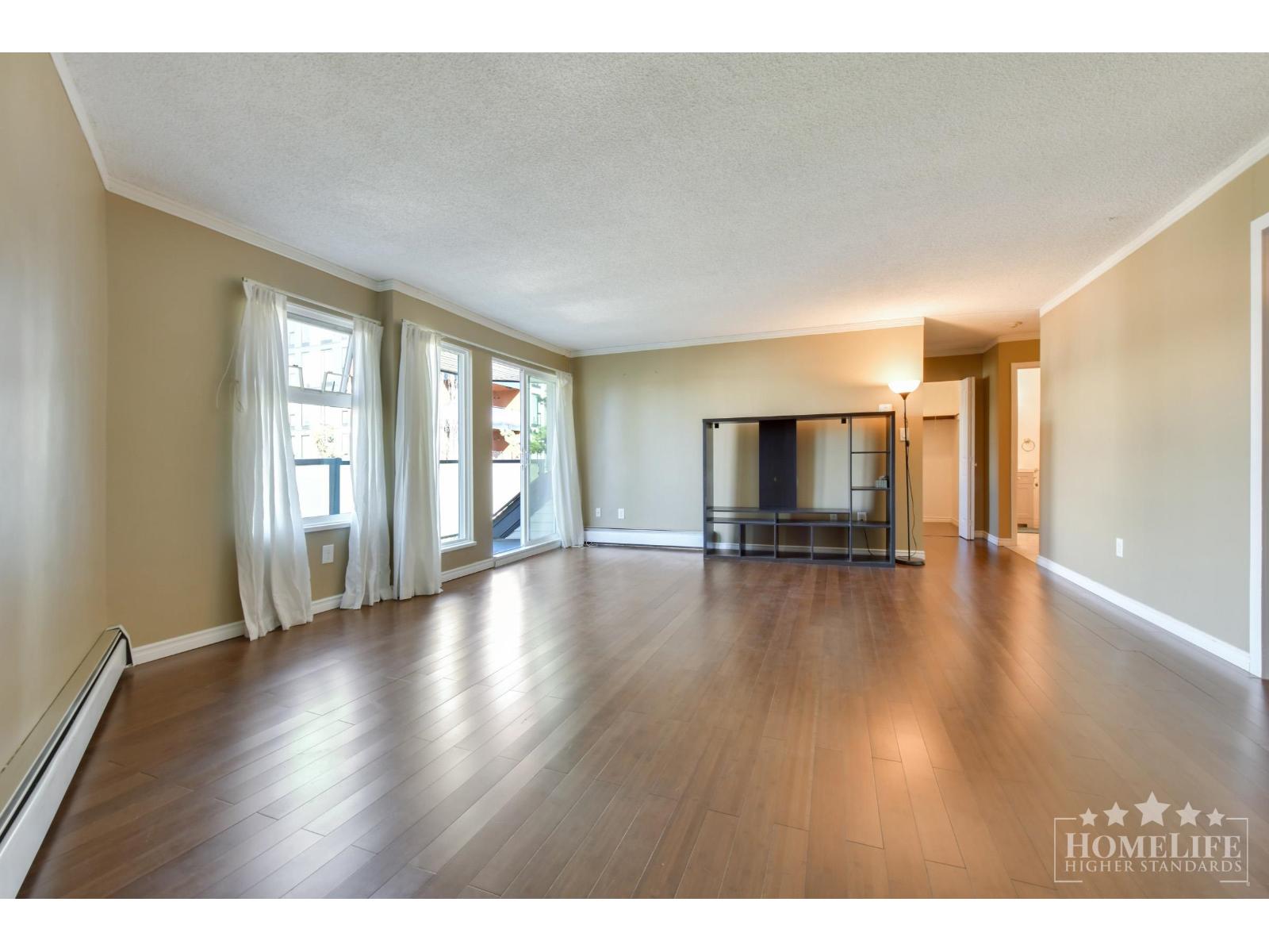A spacious living room with hardwood floors and a large window.