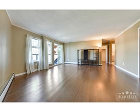 A spacious living room with hardwood floors and a large window.