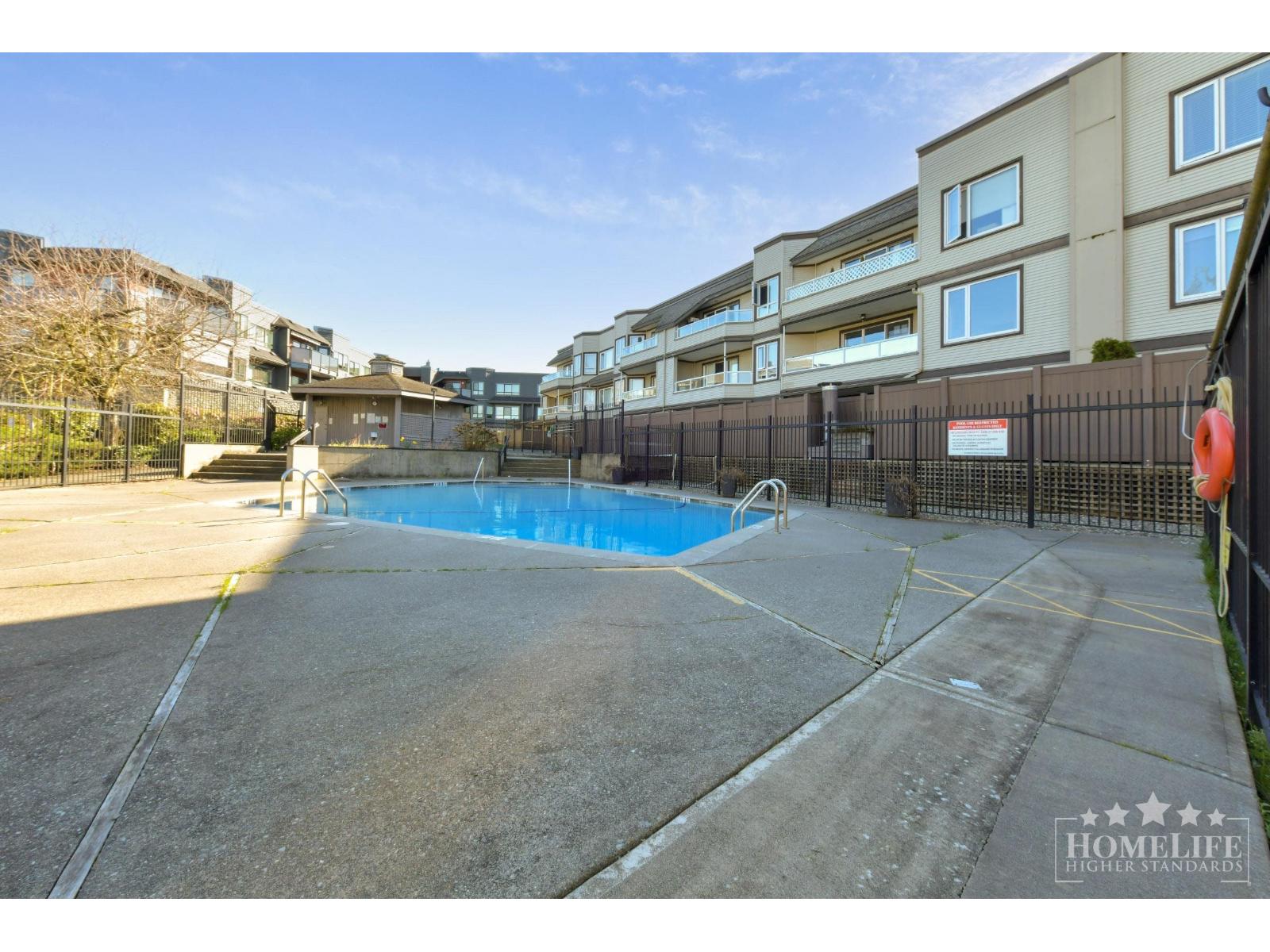 A pool surrounded by a black fence in front of a building.