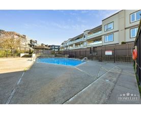 A pool surrounded by a black fence in front of a building.