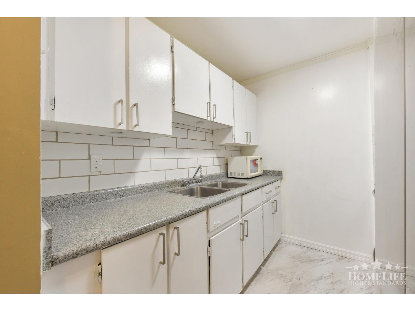 A kitchen with white cabinets and a granite countertop.