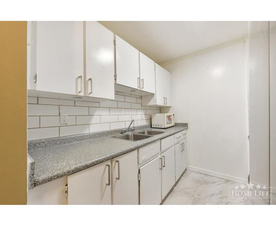 A kitchen with white cabinets and a granite countertop.