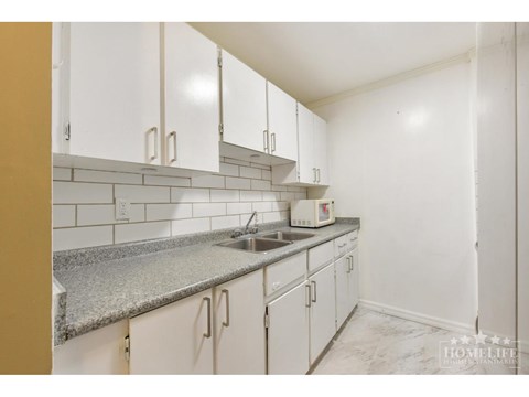 A kitchen with white cabinets and a granite countertop.