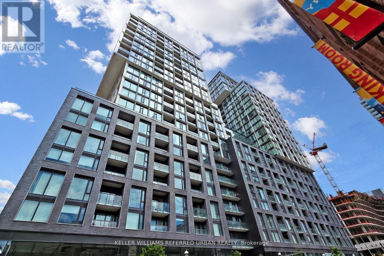 A tall building with a crane in the background and a sign that says "Keller Williams Referred Urban Brokerage".