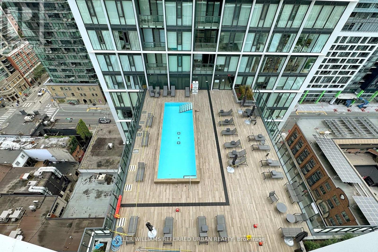 A swimming pool on a rooftop patio surrounded by chairs.