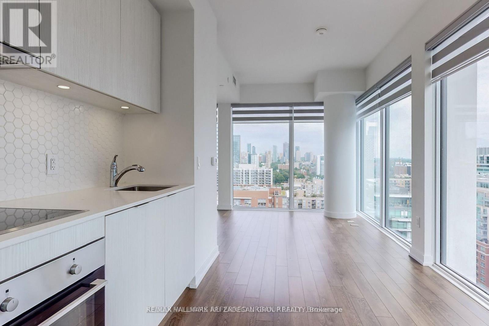 A kitchen with white cabinets and a view of the city.