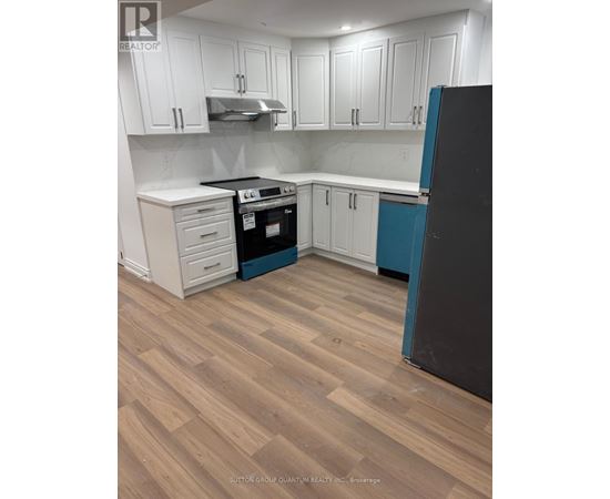 A kitchen with white cabinets and a black refrigerator.