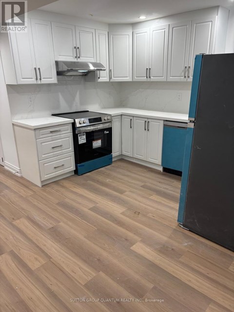 A kitchen with white cabinets and a black refrigerator.