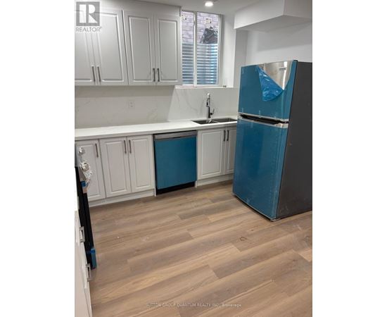 A kitchen with a blue refrigerator and white cabinets.
