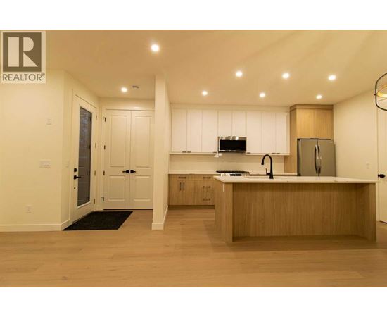 A modern kitchen with wooden cabinets and a black mat on the floor.