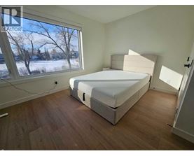 A bedroom with a large bed and a window showing a snowy landscape outside.
