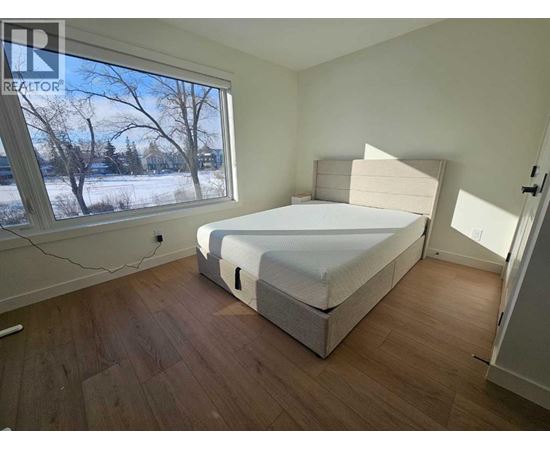 A bedroom with a large bed and a window showing a snowy landscape outside.