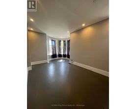 A spacious room with a dark floor and a large window with curtains.
