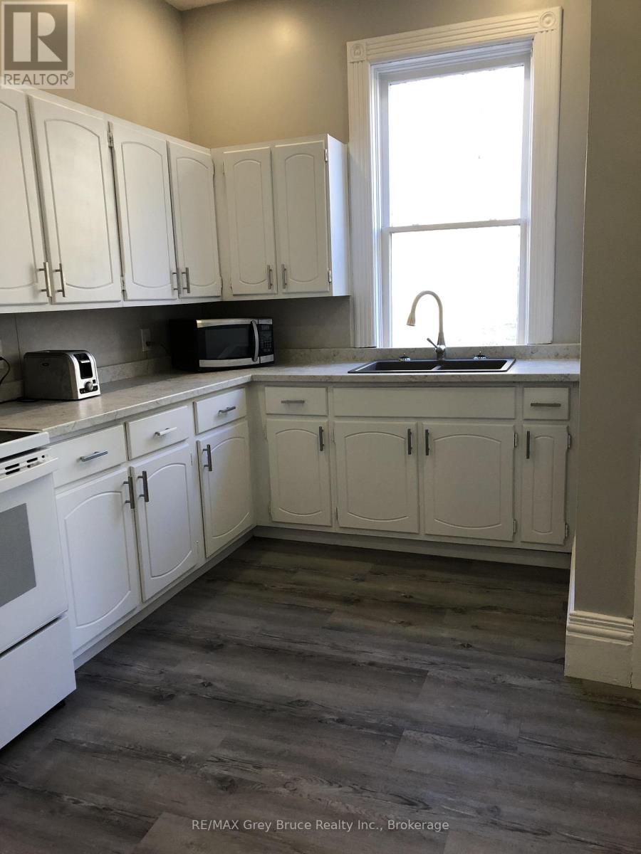 A kitchen with white cabinets and a window.