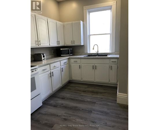 A kitchen with white cabinets and a window.