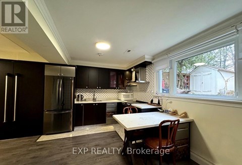 A kitchen with dark wood cabinets and a stainless steel refrigerator.