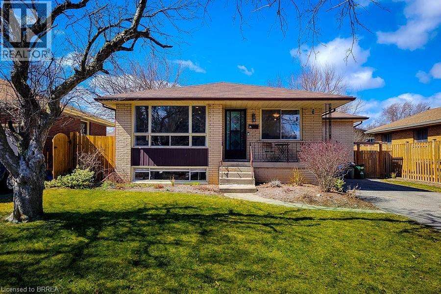 A house with a brown roof and a front yard with a tree.