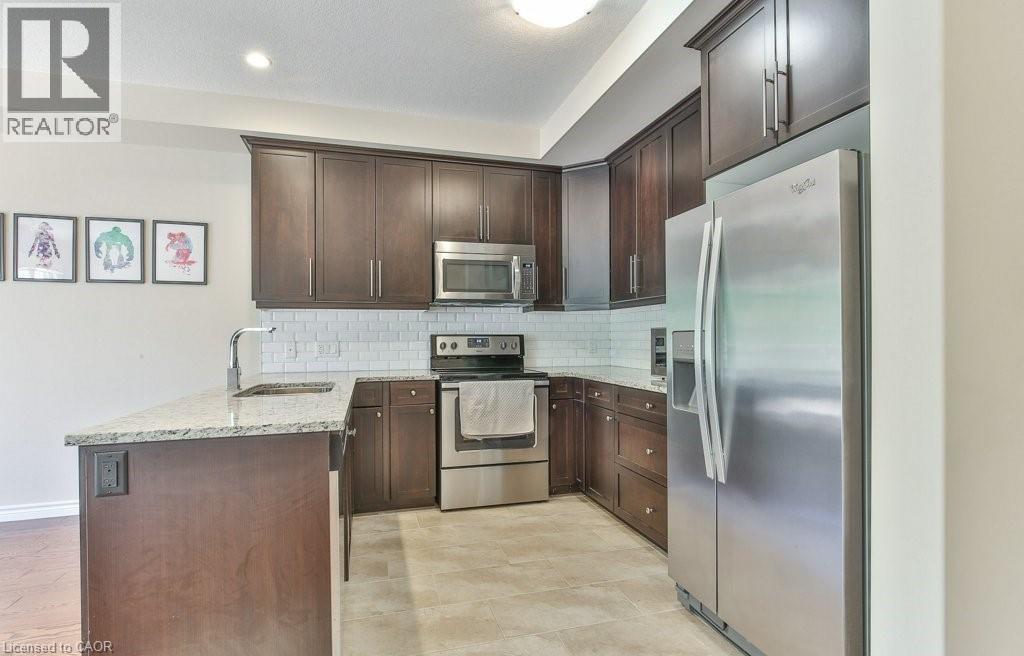 A kitchen with a refrigerator, microwave, and oven.
