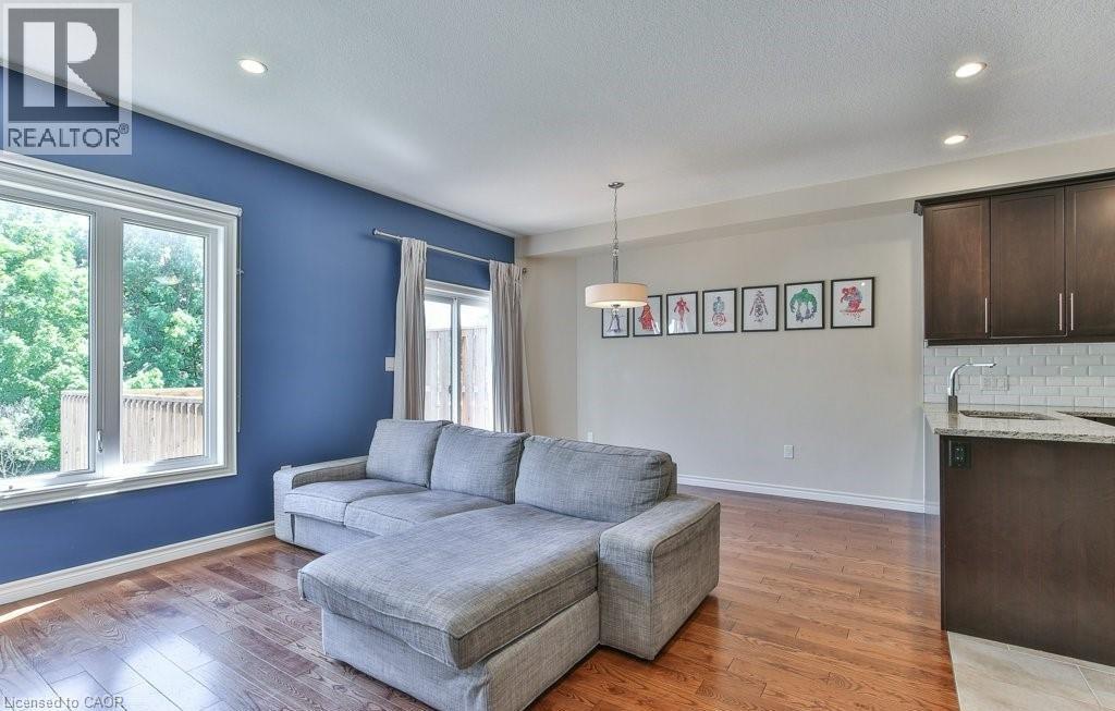 A living room with a grey couch and a kitchen area in the background.