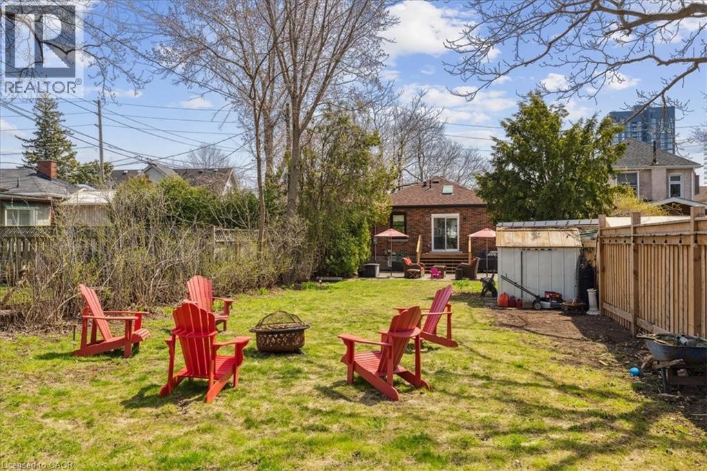 A backyard with red chairs and a basket on the grass.