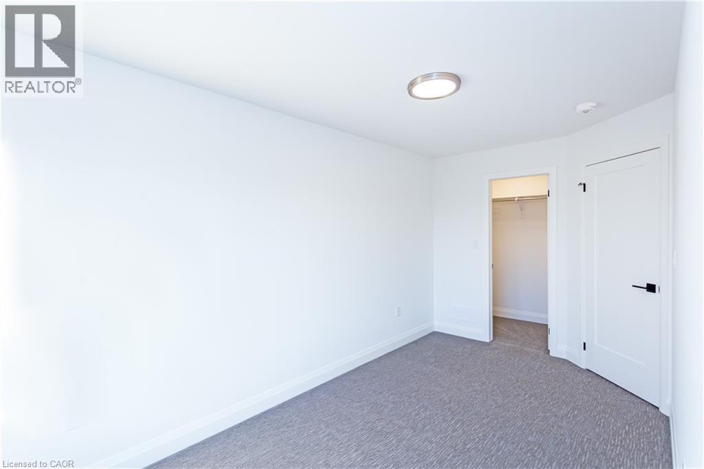 A white bedroom with a carpeted floor and a ceiling light.