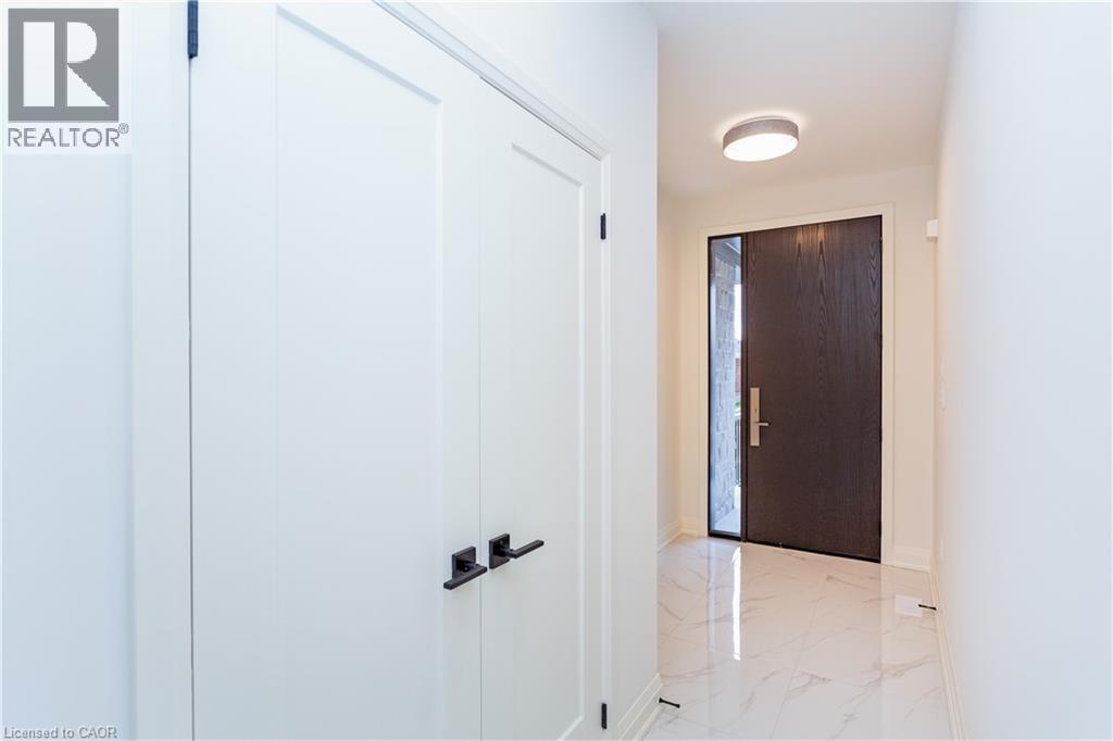 A white door with a black handle is in a hallway with a marble floor.