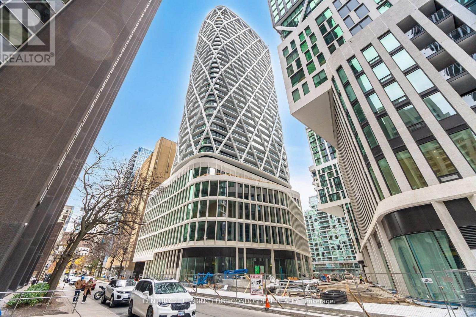 A modern building with a unique curved glass facade stands out in a cityscape.