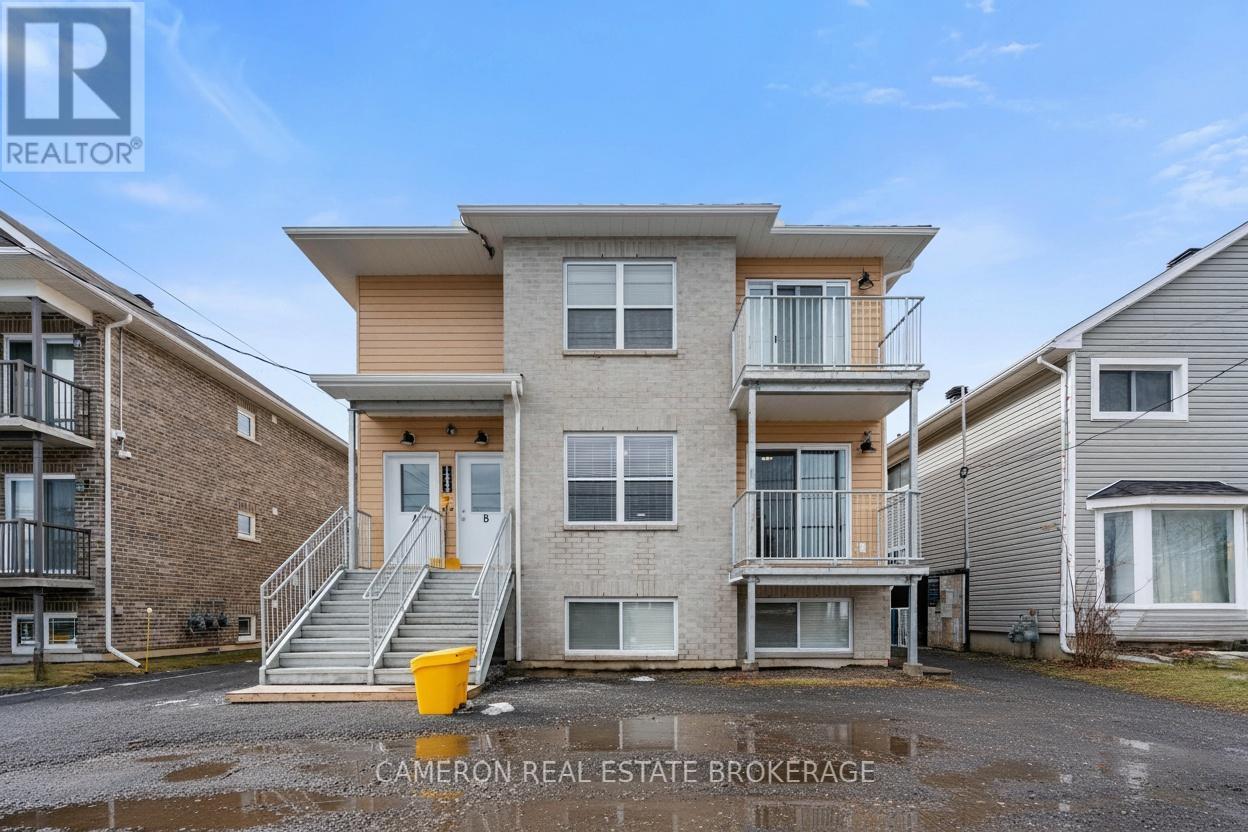 A real estate brokerage photo of a two-story townhouse with a balcony and a garage.
