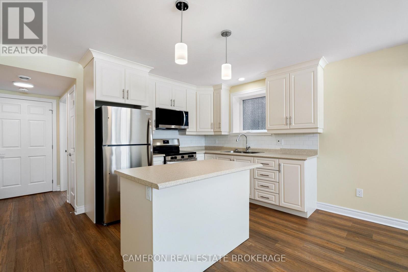 A kitchen with white cabinets and a stainless steel refrigerator.